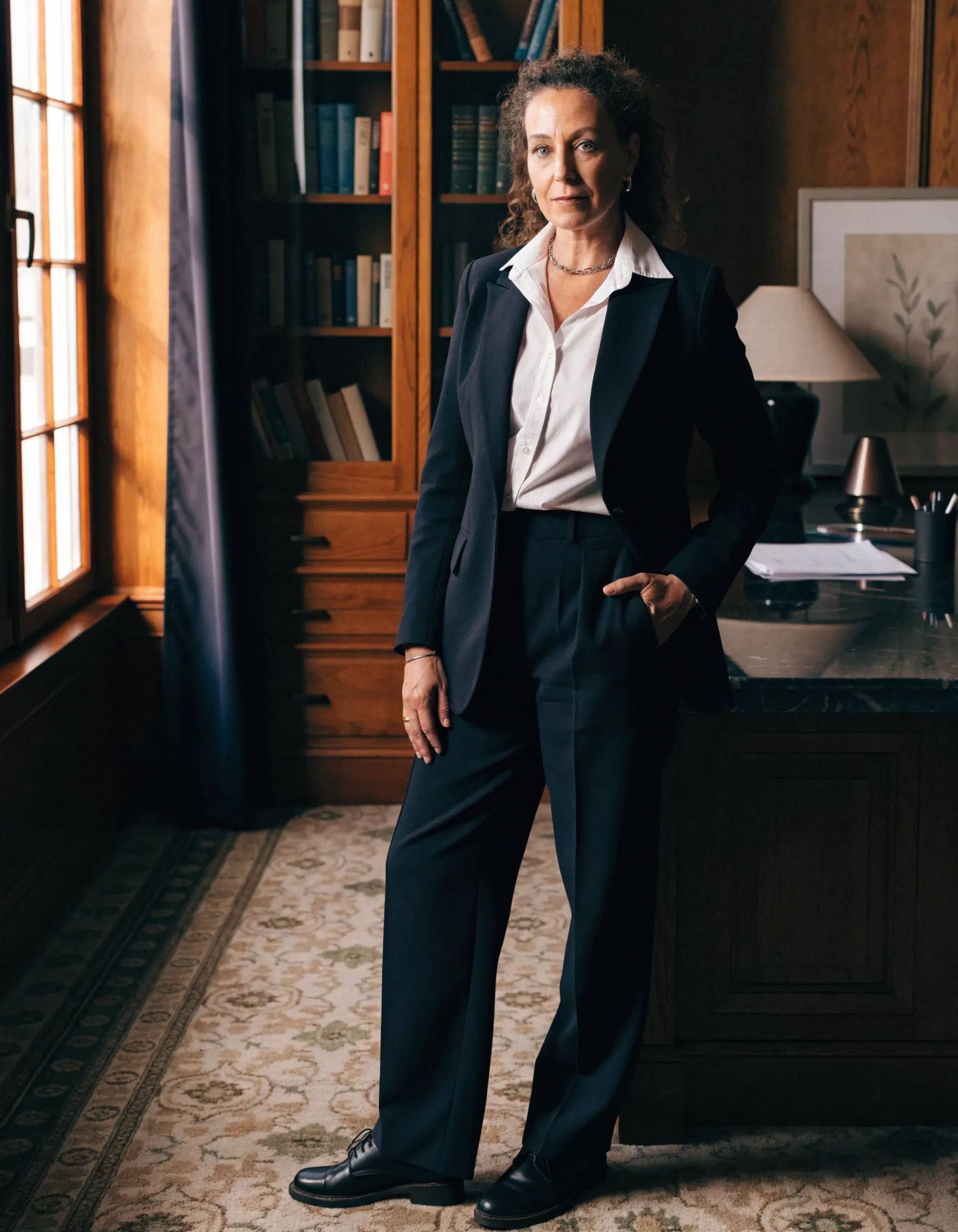 Maître Hélène Ferrand en robe d’avocate, debout près de la fenêtre de son bureau