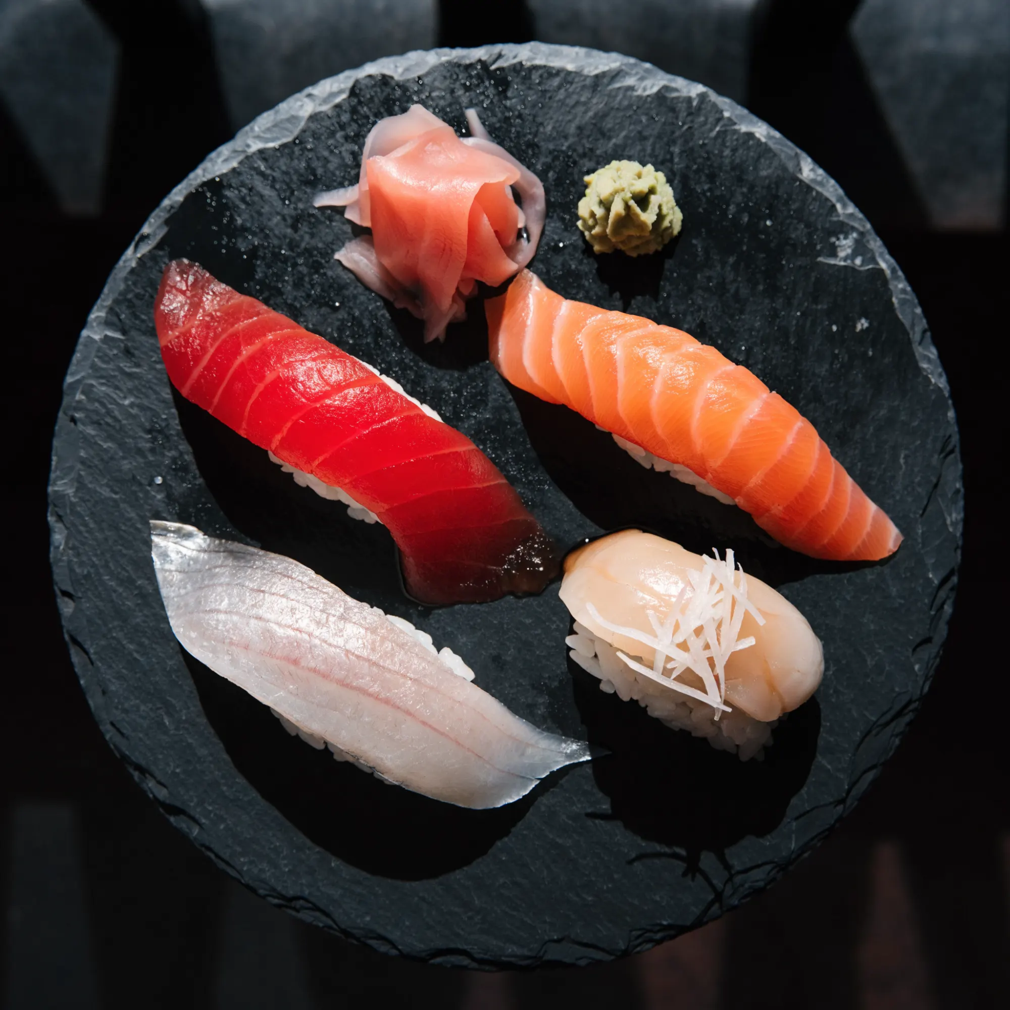 Nigiri posés un à un sur une planche de bois sombre pendant le service omakase
