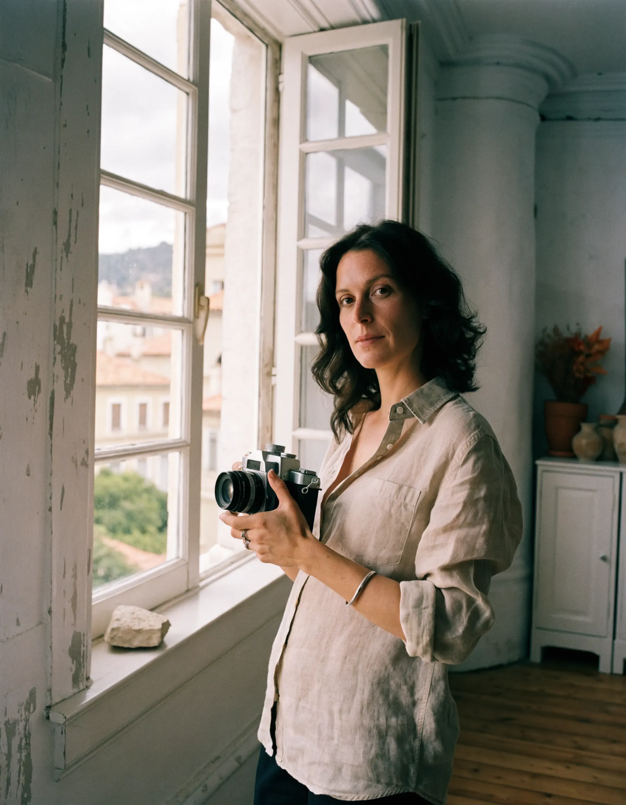 Camille Aubert dans son studio marseillais, un appareil photo argentique à la main, près d’une grande fenêtre