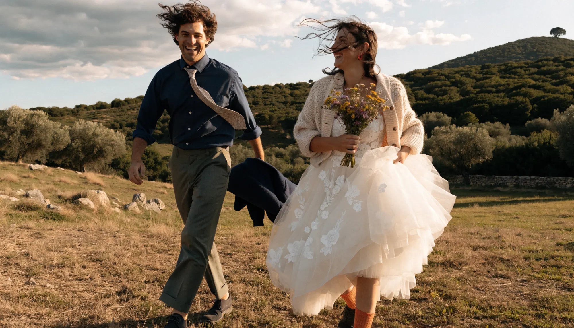 Couple de mariés marchant main dans la main dans la garrigue, en fin de journée