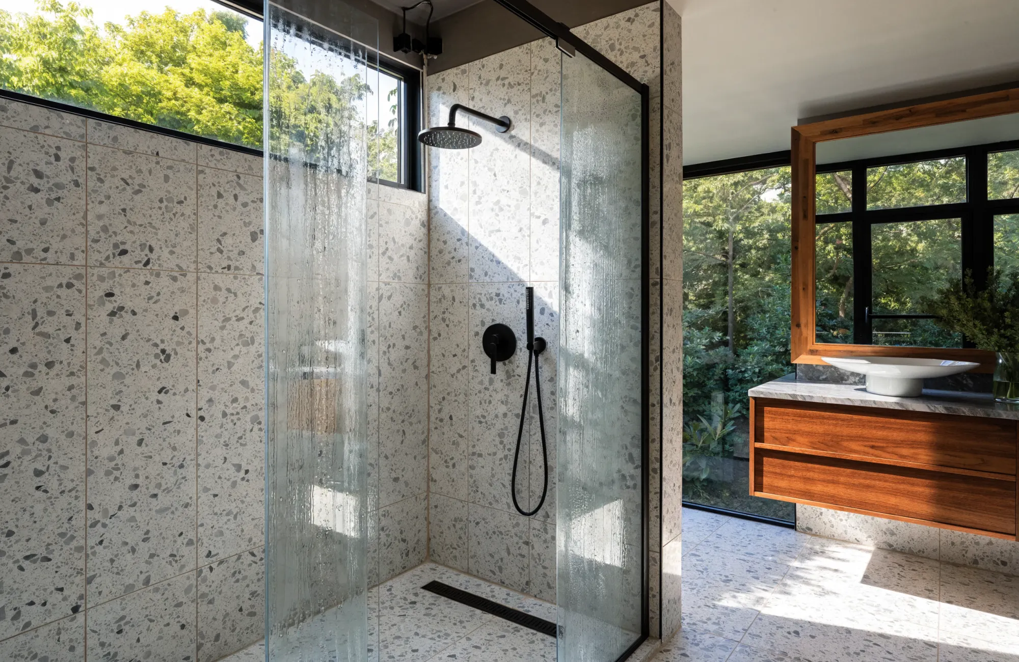 Salle de bain rénovée par Flux : vasque sur plan bois, faïence claire et douche ouverte